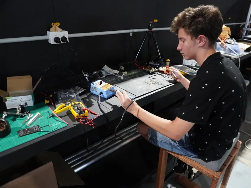 Young club member practising soldering at the workbench